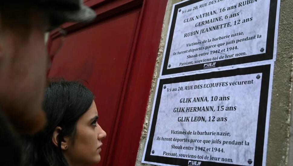 Person read posters bearing names of Jewish children deported by Nazis, displayed on the building where they lived, in Paris, France 