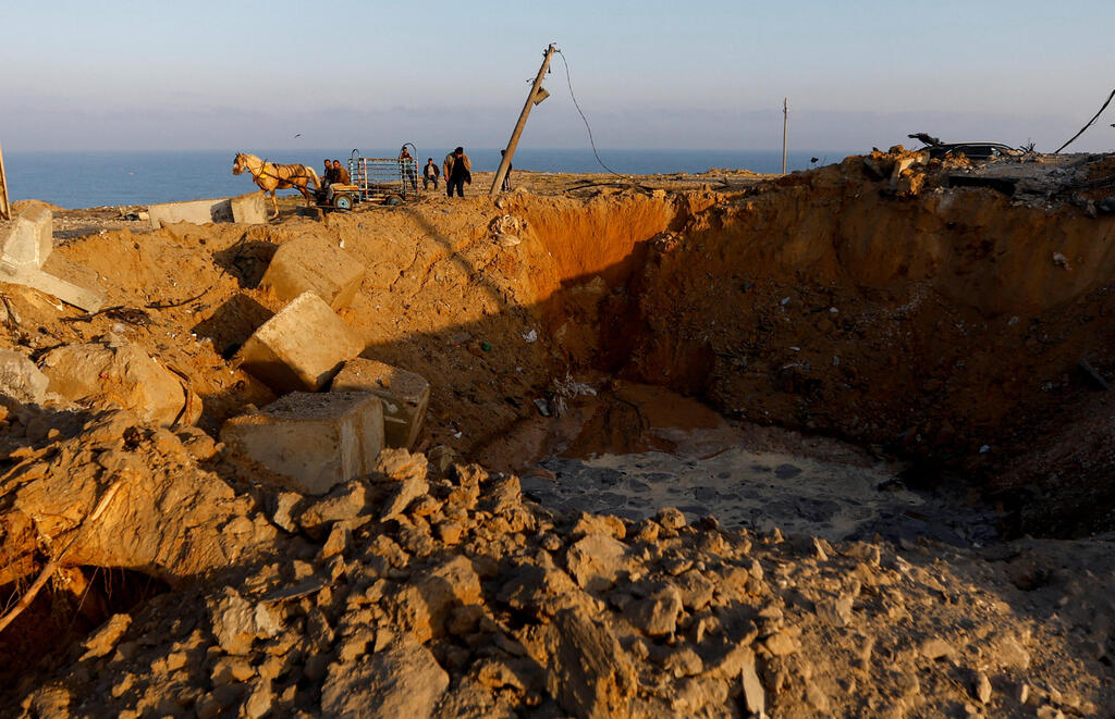פלסטינים בודקים את האתר של תקיפה אווירית ישראלית, בעיירה דיר אל-בלח