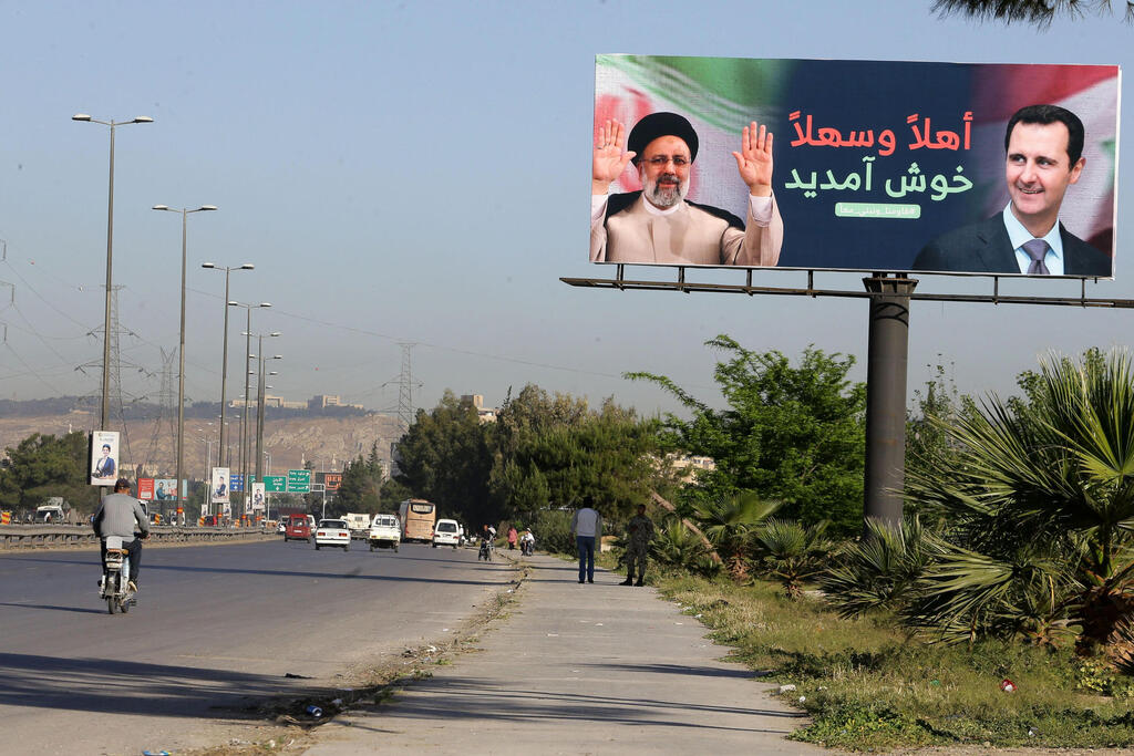 A billboard with pictures of Iranian President Ibrahim Raisi (L) and Syrian President Bashar al-Assad stands on the road leading to Damascus International Airport 