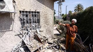 Miriam Karen gestures towards her damaged house which was hit by a rocket from Gaza for the second time in five years, in Ashkelon 