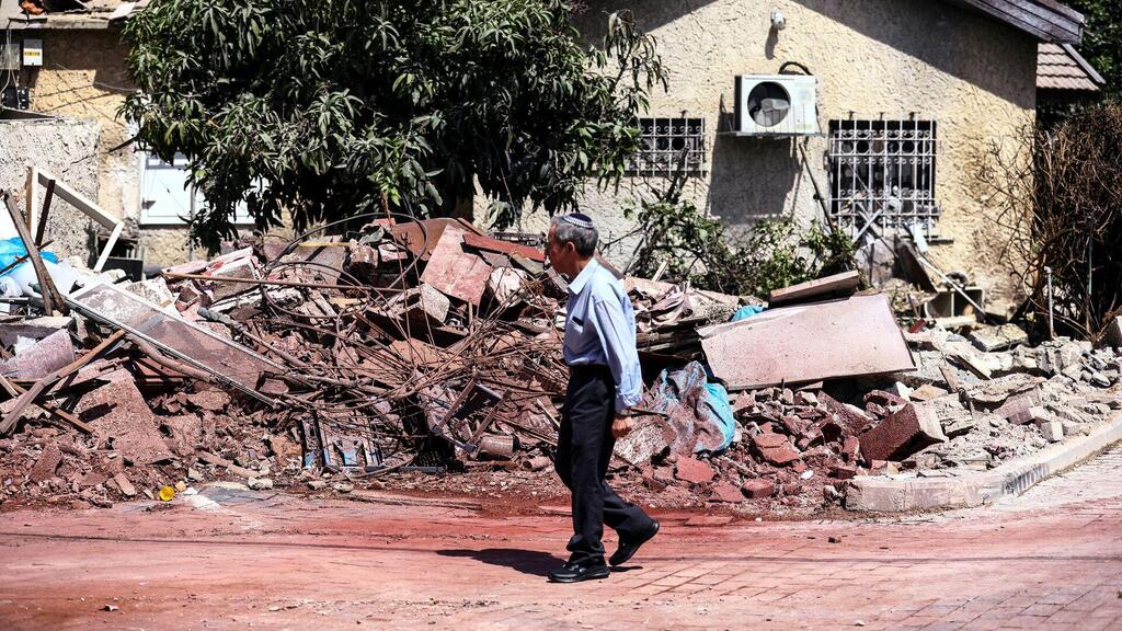  A man walks by a home that was damaged when a rocket, fired from Gaza, hit it in Ashkelon 