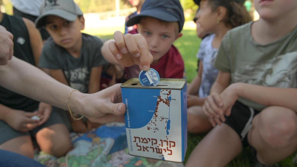 ילדים במרכז שדה ציפורי שמים מטבע בקופה הכחולה. (צילום: מיכאל חורי ארכיון הצילומים של קק"ל) ילדים במרכז שדה ציפורי.