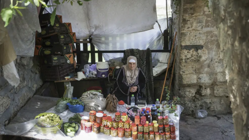 A Palestinian vendor sells produce made by farmers in the West Bank village of Battir Sunday, June 4, 2023 
