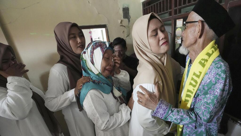 Husin bin Nisan, right, hugs relatives as he bids farewell prior to his departure for the hajj pilgrimage at his house in Tangerang, Indonesia 