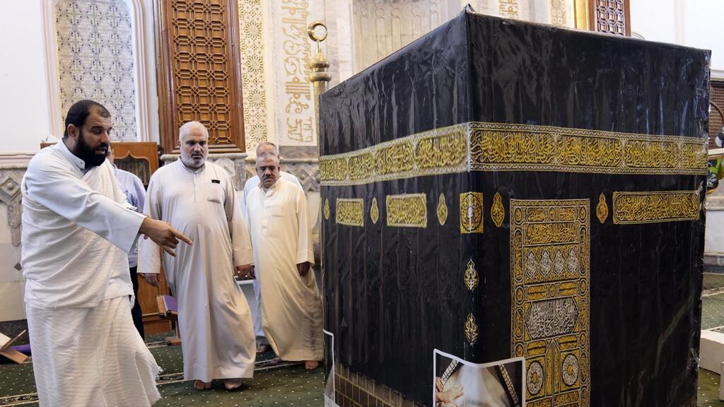 Iraqi pilgrims walk around the model of Kaaba during a lecture on performing the Hajj rituals in Tikrit, Iraq 