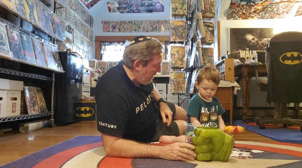 Rabbi Victor Urecki plays with his grandson in his comic book room.
