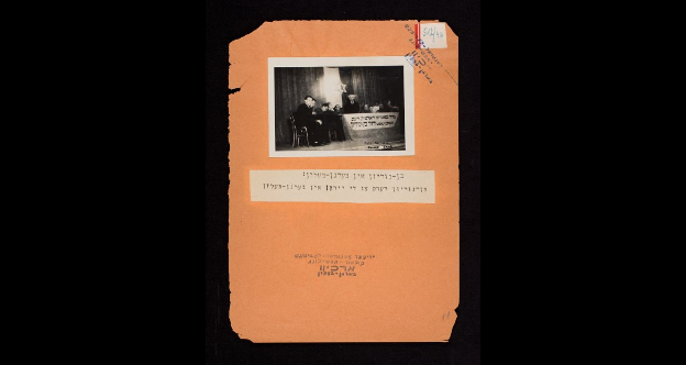 A rare photo of David Ben-Gurion visiting the Bergen-Belsen concentration camp in 1945; Above the podium where he spoke was written in Yiddish: ‘We welcome our distinguished guest, David Ben-Gurion’ (Photo: Courtesy of YIVO) A rare photo of David Ben-Gurion visiting the Bergen-Belsen concentration camp in 1945; Above the podium where he spoke was written in Yiddish: ‘We welcome our distinguished guest, David Ben-Gurion’