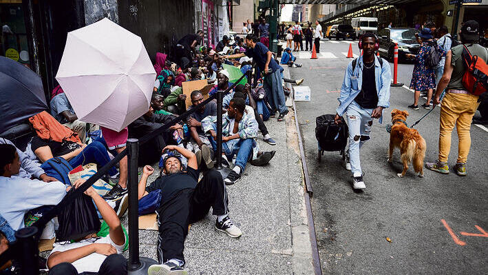 מהגרים ברחוב מחוץ לבית המחסה שאותו נאלצו לעזוב | צילום: John Minchillo, אי־פי yk13607225