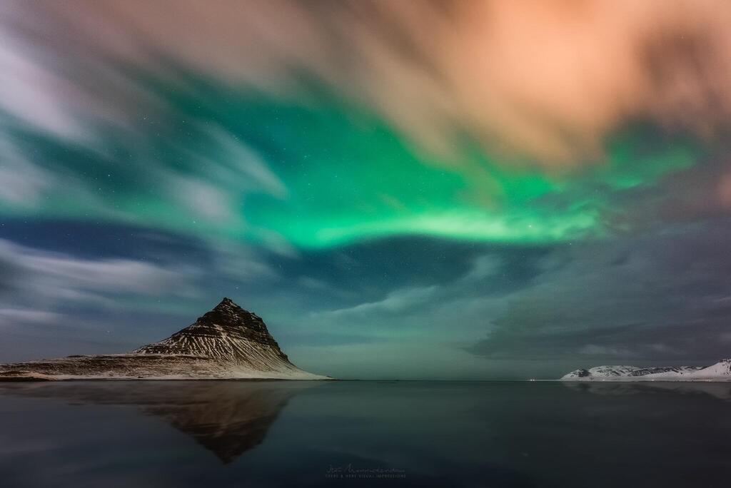 זוהר צפוני משתלב יפה עם זיהום אור ליד העיירה Grundarfjörður באיסלנד