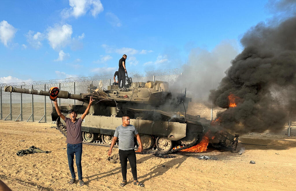 תושבים עזתים ליד הגדר במהלך הטבח (צילום: REUTERS/Mohammed Fayq Abu Mostafa) מחבלי חמאס ב-7 באוקטובר