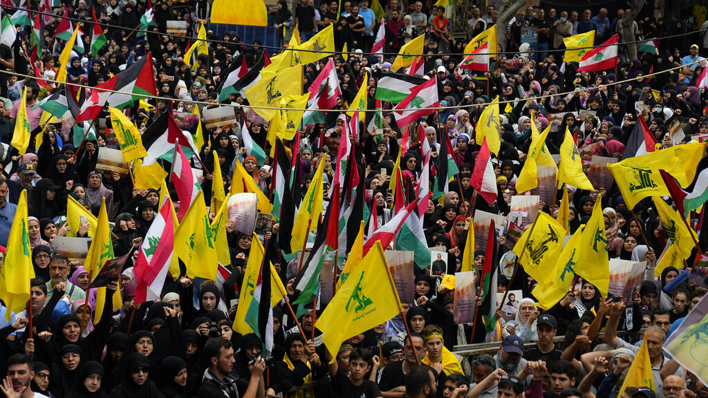 תומכי חיזבאללה מניפים דגל חיזבאלה ולבנון במהלך עצרת הזדהות עם העם הפלסטיני בעזה, שבדרום ביירות, לבנון
