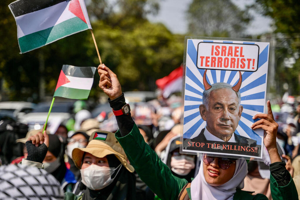 "עצרו את מעשי הרצח!". מפגינים נגד ישראל באינדונזיה, עם תמונת נתניהו כשטן ( צילום: BAY ISMOYO / AFP) חרבות ברזל ג'קרטה אינדונזיה מפגינים נגד ישראל בעד פלסטינים עזה