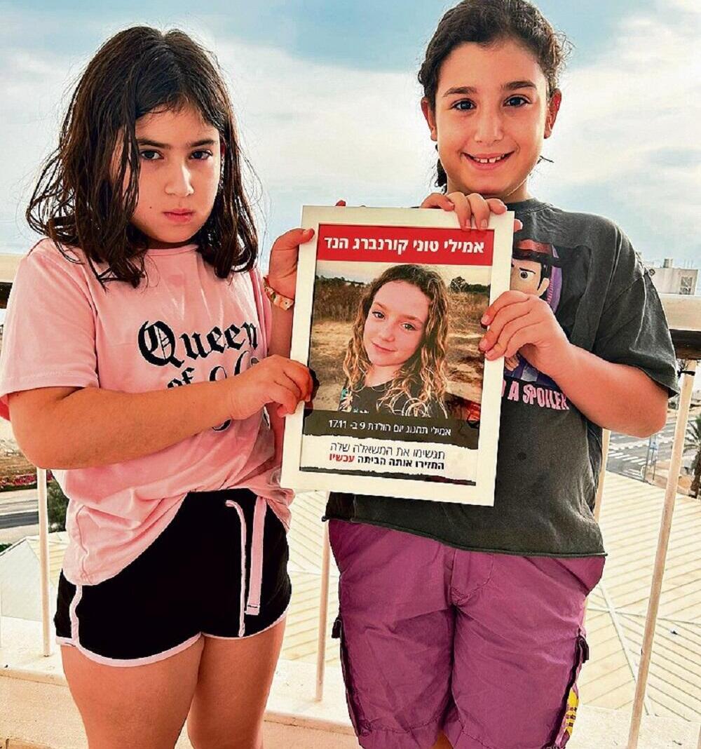 קרן וזיו אביטבול, בנות תשע, מבארי, עם תמונת חברתן אמילי קורנברג הנד, החטופה