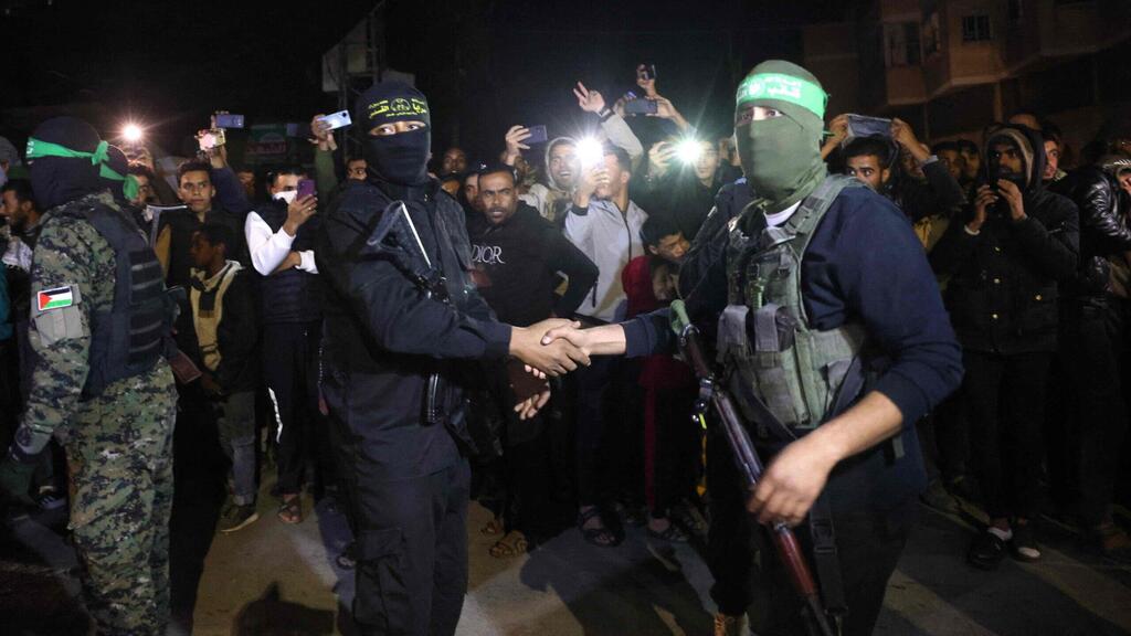 Islamic Jihad and Hamas terrorists shake hands during a release of Israeli hostages (Photo: AFP) אנשי חמאס וג'יהאד תועדו בשיתוף פעולה לראשונה