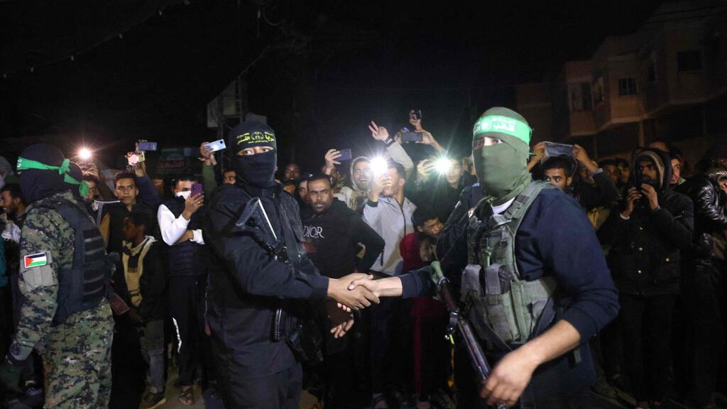 Islamic Jihad and Hamas terrorists shake hands during a release of Israeli hostages (Photo: AFP) אנשי חמאס וג'יהאד תועדו בשיתוף פעולה לראשונה