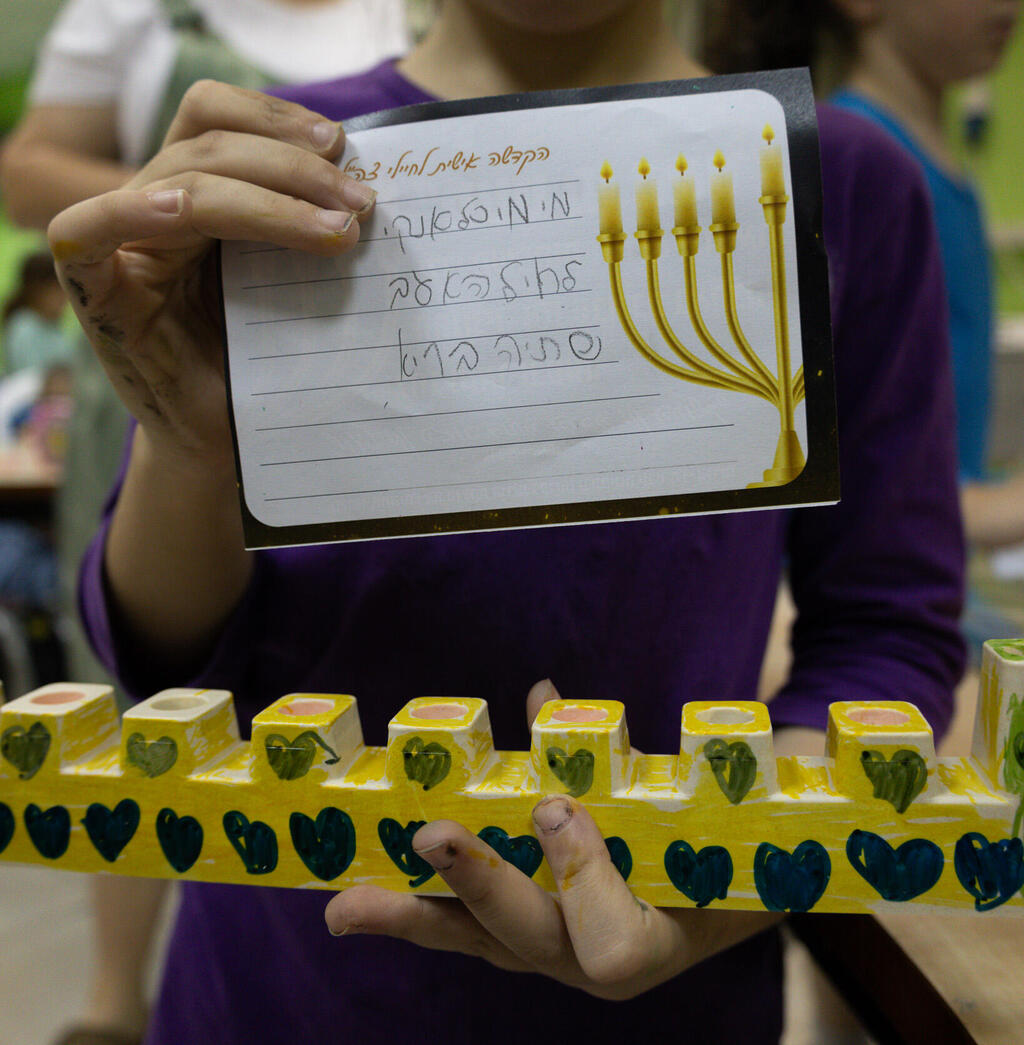 Menorahs decorated by members of the evacuated communities were sent with letters to strengthen the soldiers' morale (Photo: IDF Spokesperson's Unit) לוחמי צה"ל מדליקים נרות בתוך שטח רצועות עזה, עם חנוכיות שקושטו על ידי חברי הקהילות המפונות