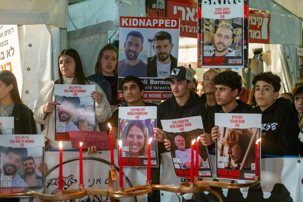 Kfar Aza residents holding signs of hostages on seventh day of Hanukkah (Wednesday) (Photo: Ido Erez) תושבי כפר עזה אוחזים בתמונות החטופים שעדיין בשבי, בהדלקת הנר השביעי