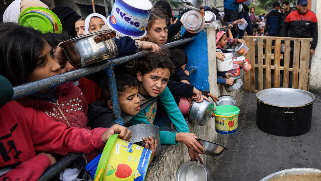 Displaced Gazans line up for food (Photo: Mahmud Hams / AFP) פליטים פלסטינים בתור למזון ב רפיח בצל עדויות על רעב ב רצועת עזה