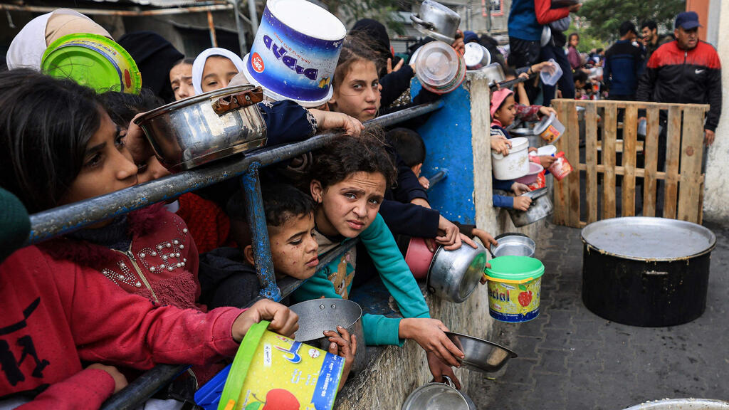 Palestinian refugees line up for food in Rafah (Photo: MAHMUD HAMS / AFP) פליטים פלסטינים בתור למזון ב רפיח בצל עדויות על רעב ב רצועת עזה