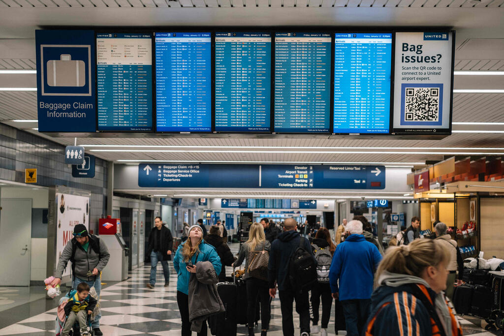 מביטים בלוח הטיסות בנמל התעופה בשיקגו. מטוסים קורקעו (צילום: Jim Vondruska / GETTY IMAGES NORTH AMERICA / AFP) לוח הטיסות בנמל התעופה אוהייר, שיקגו, אילינוי, ארצות הברית, בעקבות הסופה