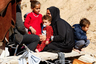 Displaced Gazans sit outside a tent in Rafah 