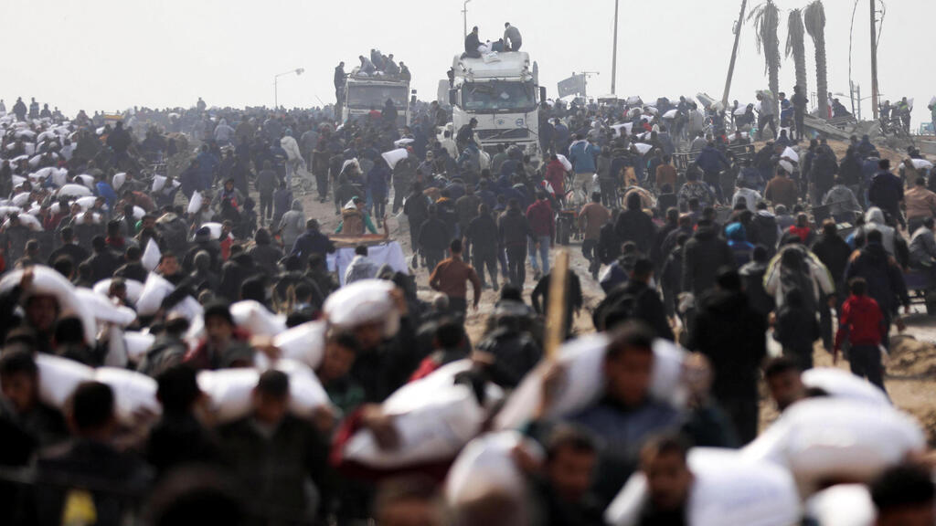 Palestinians rushing toward aid trucks in Gaza (Photo: REUTERS/Kosay Al Nemer) עזתים מתנפלים על משאיות הסיוע ברצועה