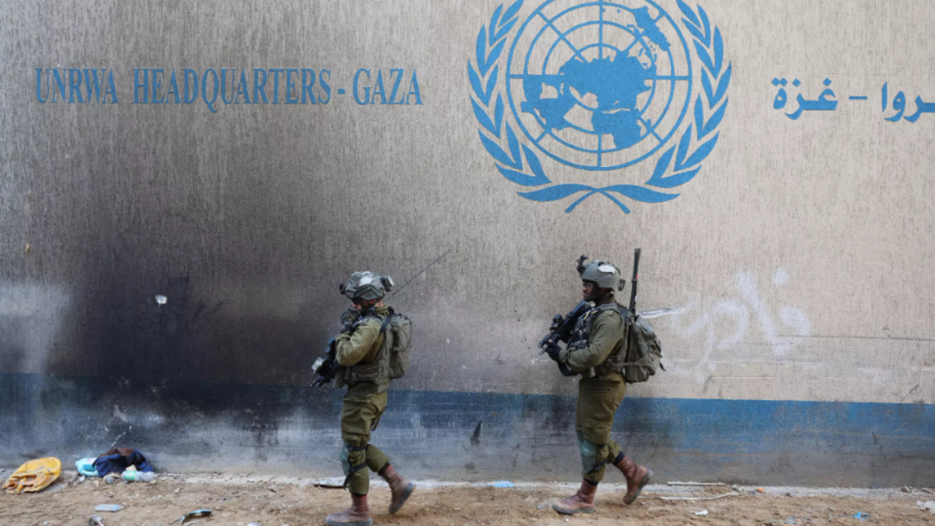 לוחמי צה"ל ליד מטה אונר"א בעזה (צילום: JACK GUEZ / AFP) לוחמי צה"ל לצד סמל של אונר"א ברצועת עזה ארכיון