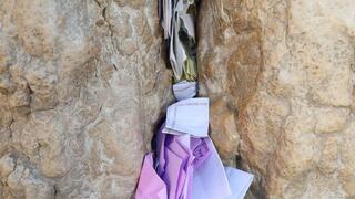Notes and prayers clog the spaces <mark>between</mark> the stones of the Western Wall