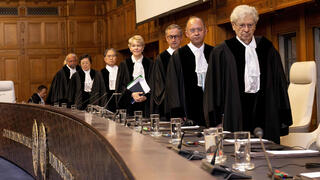 Court's president Joan Donoghue (C) and associate judges arrive to hear South African arguments to the International Court of Justice