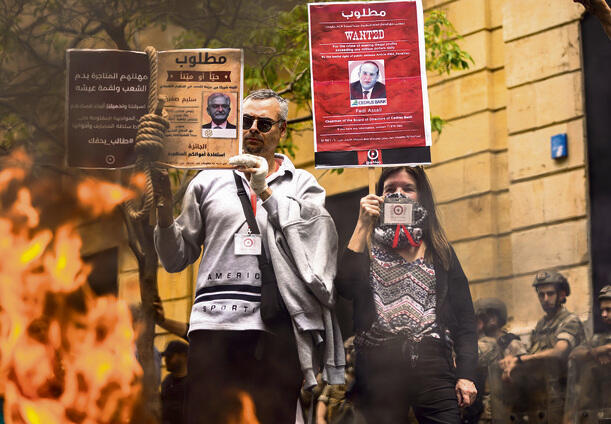 Lebanese citizens protest restriction of their bank accounts; one of the signs features a picture of Governor Riad Salameh, who is suspected of embezzling $330 million (Photo Hassan Ammar / AP) yk14044233