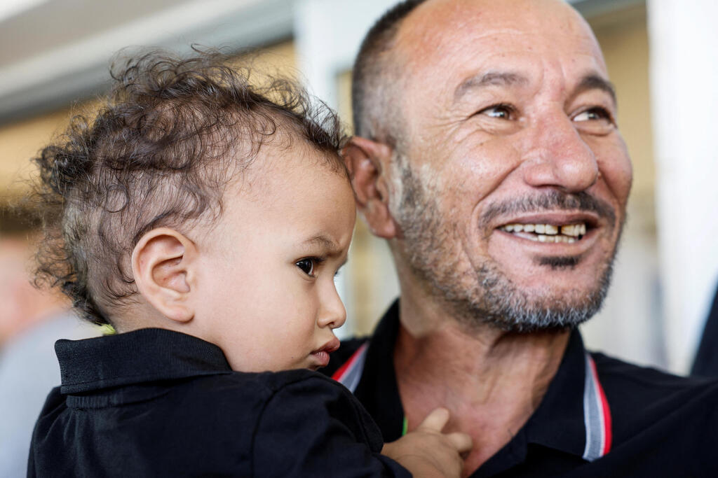 Alkadi's brother Ismail holds rescued hostage's youngest son Habib (Photo: REUTERS/Amir Cohen) איסמעיל אחיו של פרחאן קאדי
