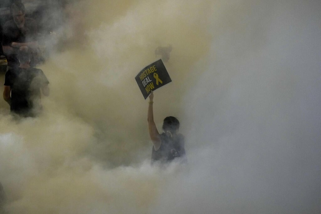 מפגינה בתל אביב עם שלט "עסקה עכשיו" (צילום: AP Photo/Ariel Schalit) תל אביב