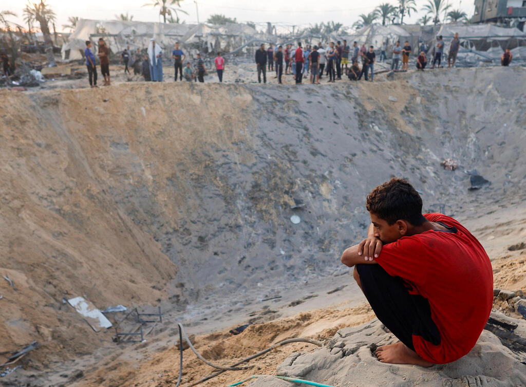 מכתש שנוצר אחרי התקיפה באל-מוואסי (צילום: REUTERS/Mohammed Salem) מכתש שנוצר בחאן יונס אחרי התקיפה