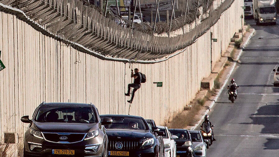 גזרת בנימין: פלסטיני עובר את גדר ההפרדה סמוך למחסום קלנדיה (צילום: JOHN WESSELS / AFP) yk14100874