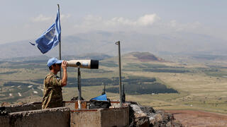 A United Nations Truce Supervision Organization military observer uses binoculars near the border with Syria in the Golan Heights, Israel, May 11, 2018 