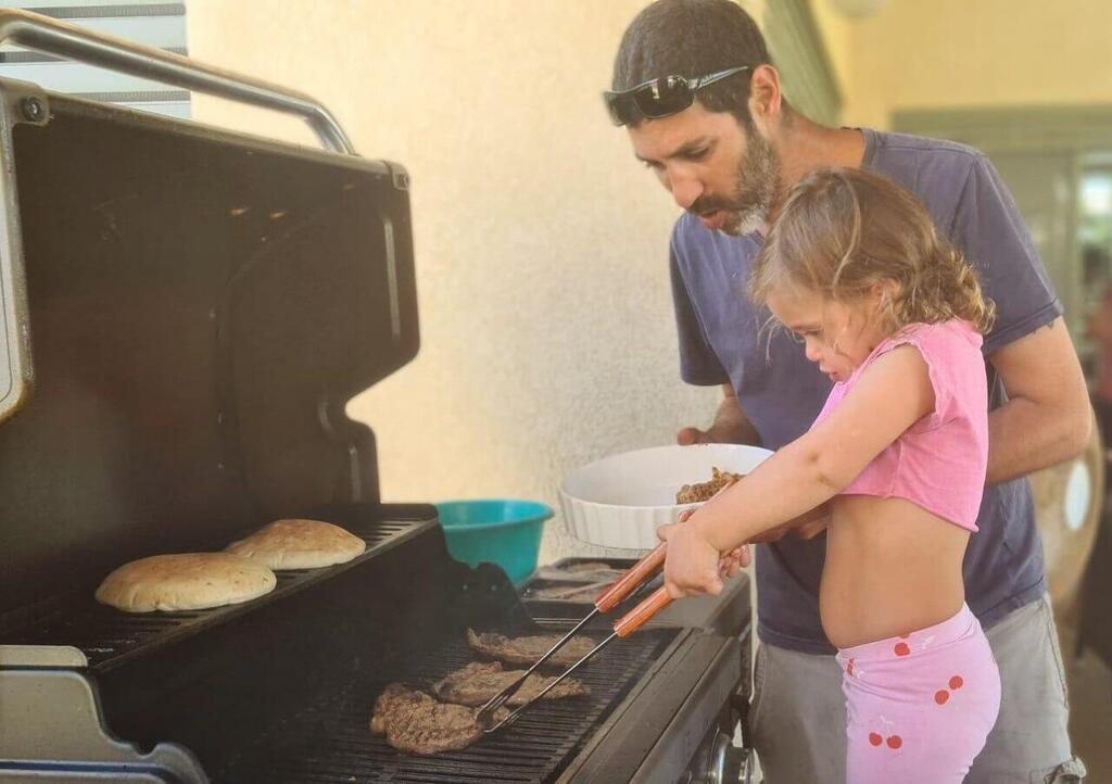 Tamir Adar shows his kids how to operate the barbeque before his abduction to Gaza (Photo: Courtesy of the family) תמיר אדר ז"ל בשנה שעברה עם משפחתו