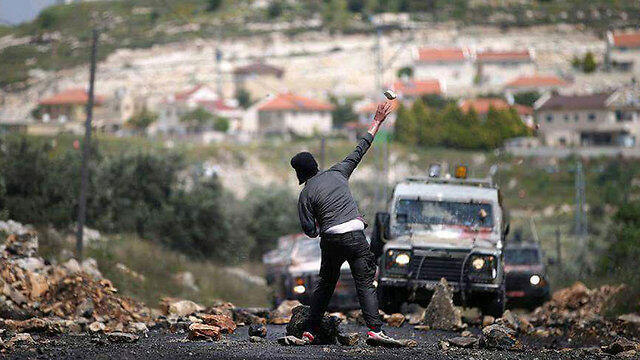 A Palestinian throws rocks at military vehicles during previous clashes in the West Bank. (Photo: Ahmed Tala'at)