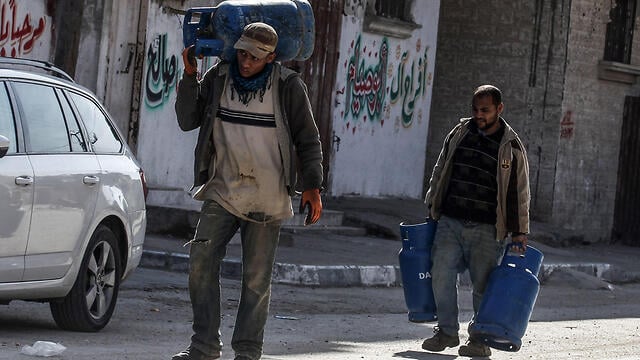 Men in Gaza carrying water home for lack of running water