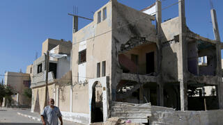 A Palestinian man walks outside a house that was damaged by Israeli strikes during Israel-Hamas fighting last May, in Khan Younis in southern Gaza Strip 