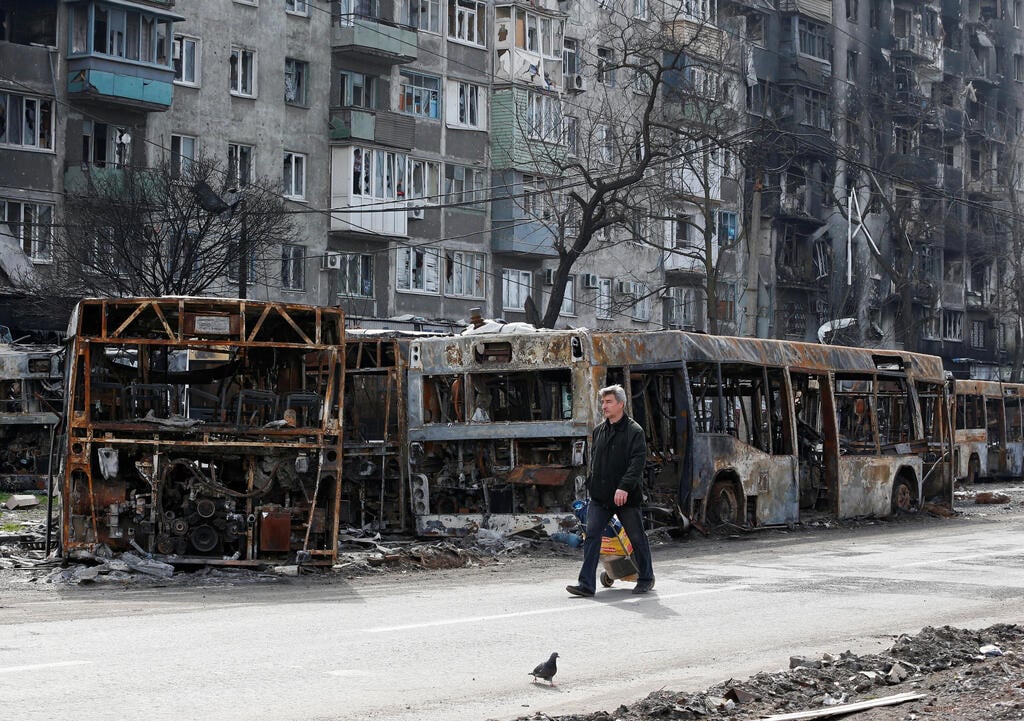 Civilian walks past charred buses amid Russian siege of Mariupol (Photo: Reuters) הרס במריופול