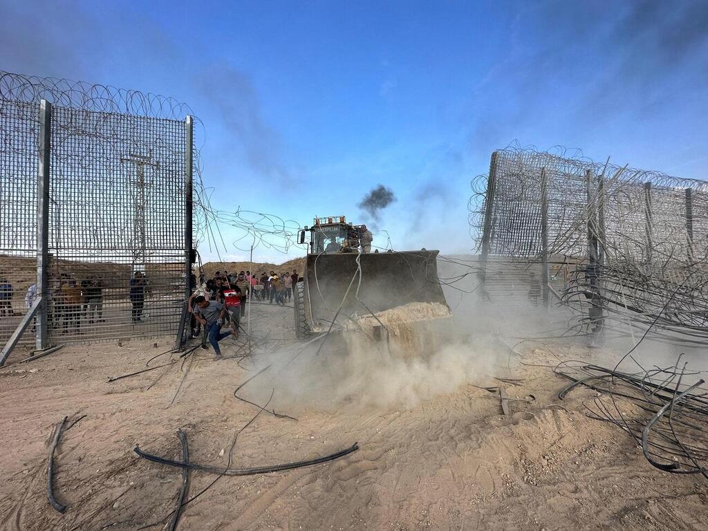 Hamas terrorist breaking down the border fence on October 7 (Photo: Reuters) פריצת הגדר בגבול עזה
