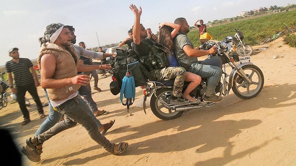 Hamas terrorists take a hostage into Gaza on October 7, 2023 (צילום: AP) מחבלי חמאס ב־7 באוקטובר