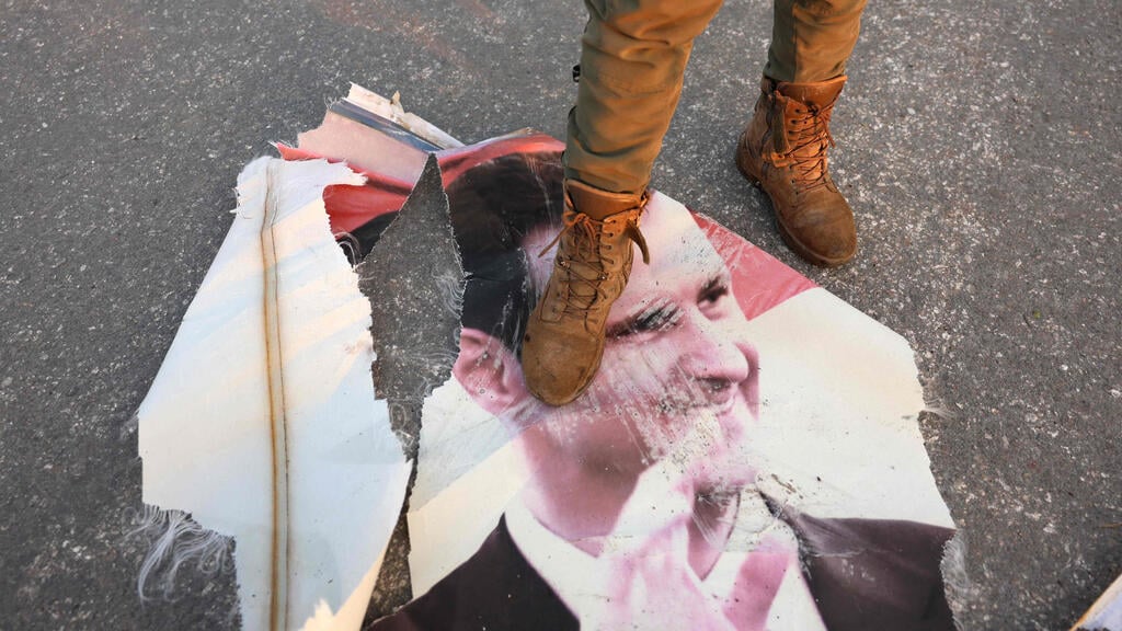 Rebel steps on a portrait of Syrian President Bashar al-Assad (Photo: Mohammed AL-RIFAI / AFP) מורד ב חמה דורך על תמונת דיוקנו של נשיא סוריה בשאר אל אסד