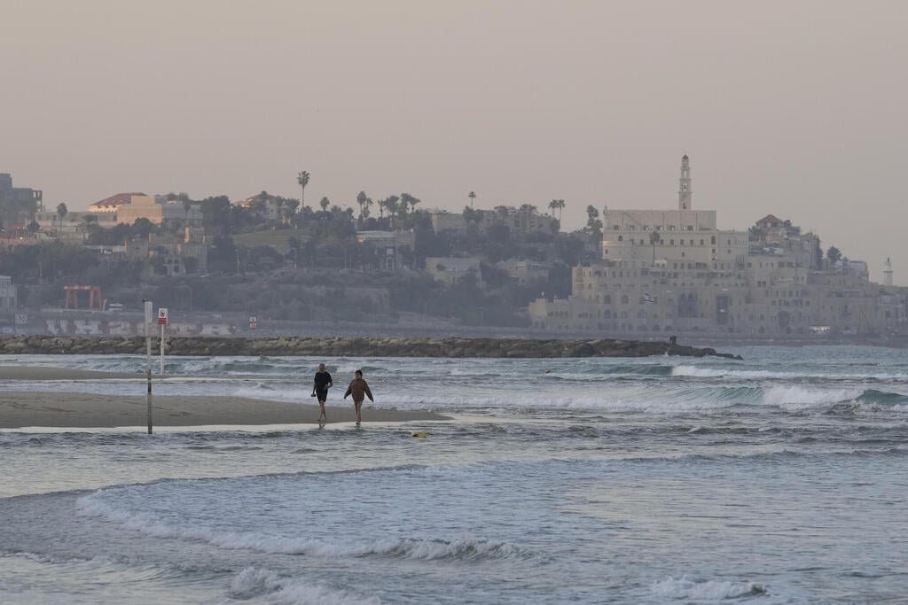 Tel Aviv beach (Photo: AP Photo/Matias Delacroix) מטיילים בחוף הים בתל אביב-יפו