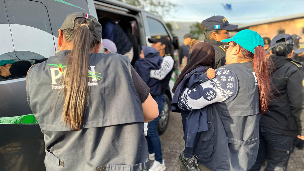 Guatemalan forces during the rescue operation (Photo: Guatemalan Attorney General of the Nation's Office / AFP) שוטרות נושאות ילדים בידיהן לרכב המשטרתי