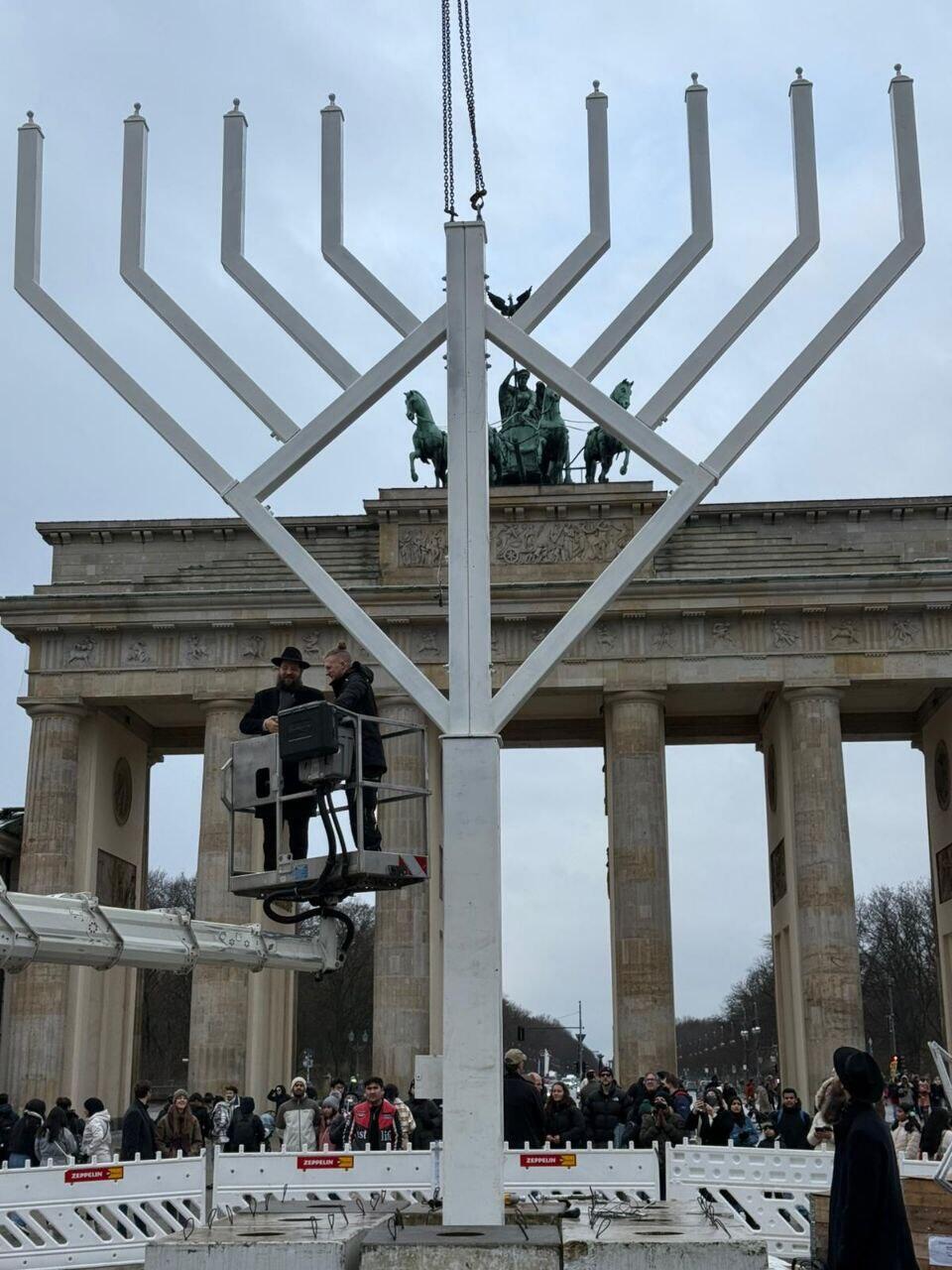 החנוכייה ליד שער ברנדנבורג בברלין. לא יוצאים ידי חובה בהדלקות הציבוריות (צילום: באדיבות חב"ד) תיירים וצלמי תקשורת צופים ומתעדים את הצבת החנוכייה למרגלות שער בנדרבורג בברלין