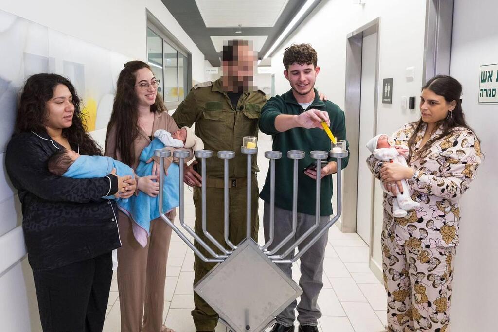 Noam Levy, an IDF soldier who survived death in the war, lights a Hanukkah candle alongside Lt. Col. Dr. A, in the newborn nursery at Assuta Ashdod Hospital נועם לוי, לוחם צה”ל שניצל ממוות במלחמת "חרבות ברזל", מדליק נר ראשון של חנוכה עם רס"ן ד”ר א', הרופא שהציל את חייו בתינוקיית בית החולים הציבורי אסותא אשדוד