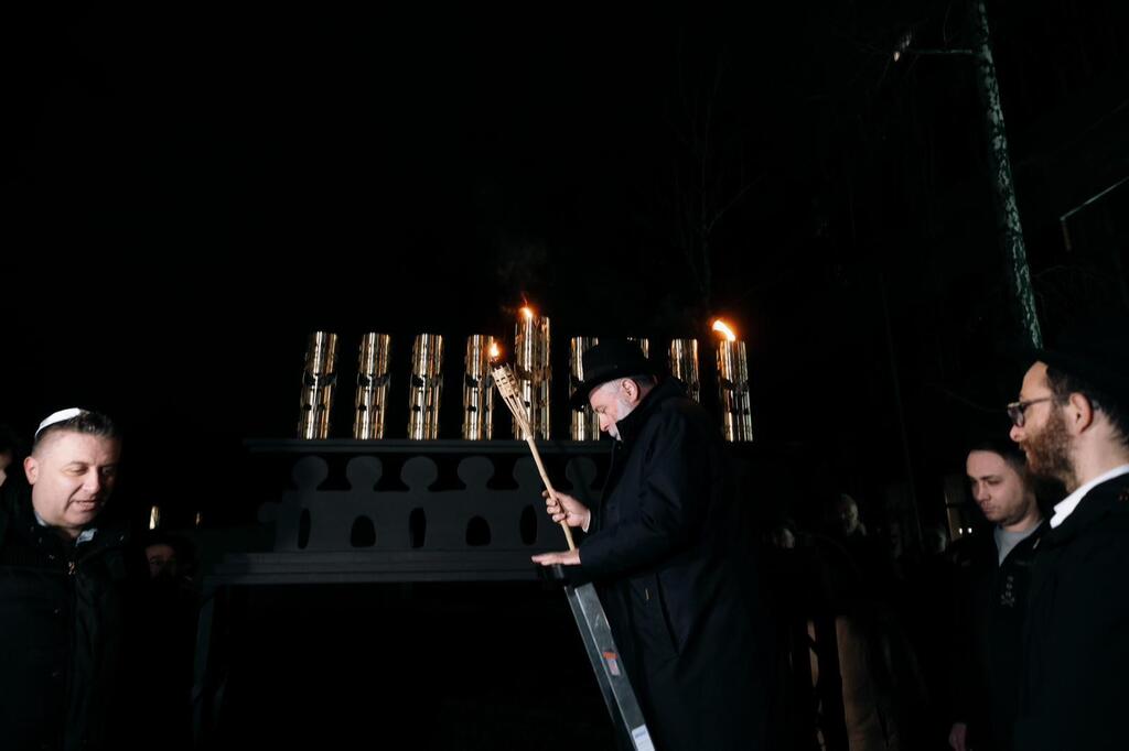 A candle is lit in Kiev at a menorah containing the remains of a Russian drone. (Photo: Jewish Community in Kiev – JCC) מדליקים נר בקייב בחנוכייה שמכילה שרידי כטב"ם רוסי. "סיפור הניצחון של האור על החושך"