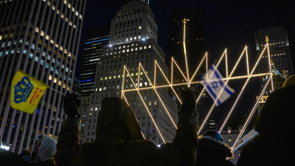 A hanukkiah in New York (Photo: Alexi J. Rosenfeld / Getty Images North America / AFP) דגל ישראל על רקע החנוכייה הגדולה בעולם