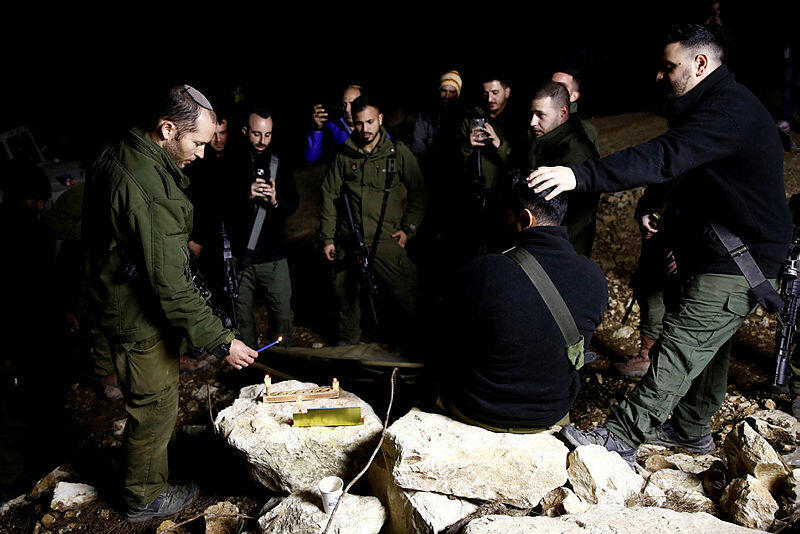 An Israeli soldier lights candles as soldiers gather to celebrate the first day of Hanukkah, near the Israeli-Lebanon border (Photo: Shir Torem/ Reuters) An Israeli soldier lights candles as soldiers gather to celebrate the first day of Hanukkah, near the Israeli-Lebanon border